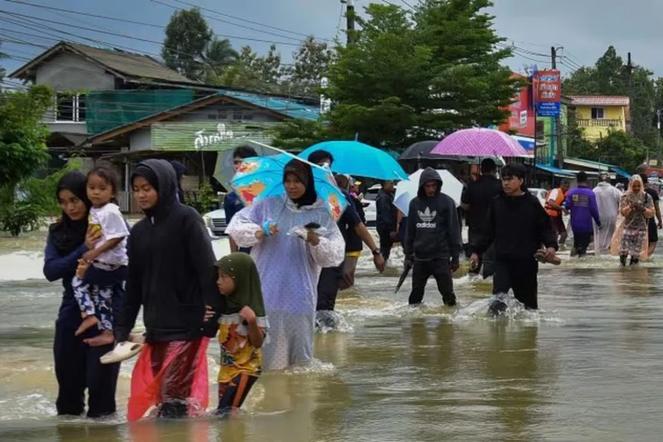 DITENGGELAMI AIR: Para penduduk di Narathiwat, wilayah selatan Thailand, mengharungi paras air tinggi untuk menuju ke tempat yang lebih selamat ekoran banjir melanda wilayah itu pada 25 Disember.
