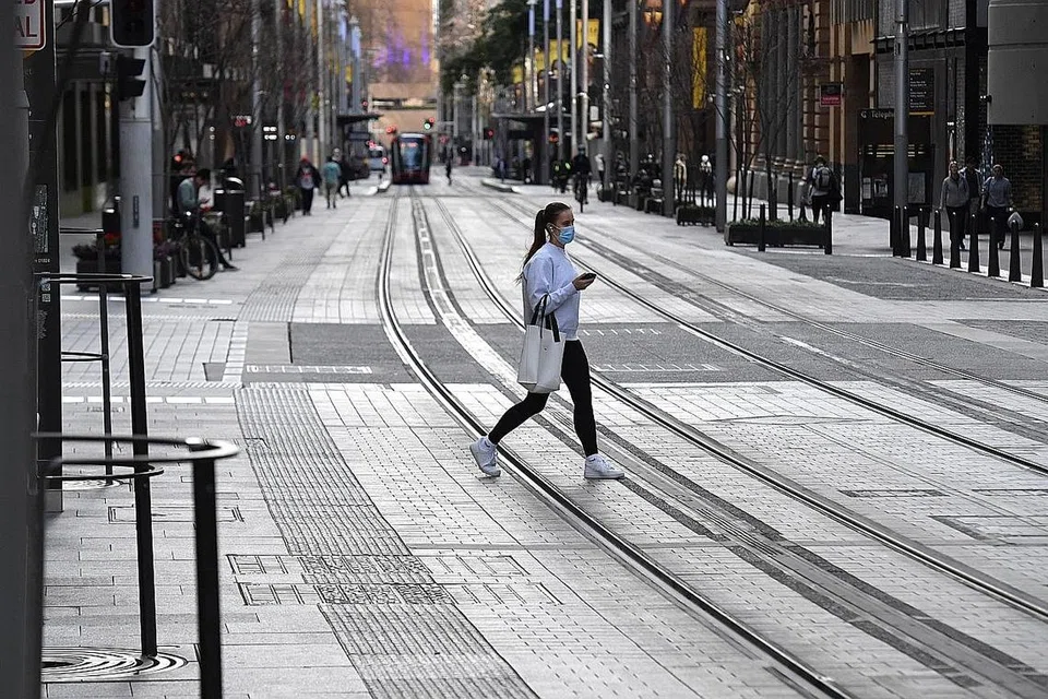 LENGANG: Seorang penduduk Sydney berjalan di kawasan pusat bandar yang lengang ekoran sekatan pergerakan yang dikenakan di ibu kota New South Wales, Australia, itu. - Foto EPA-EFE