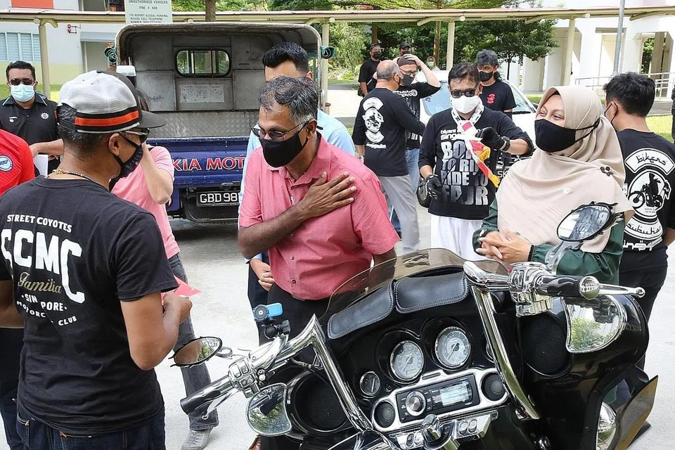 UCAP TERIMA KASIH: Encik Murali (berbaju merah) menyertai pengedaran makanan di Blok 210A Bukit Batok Street 21 semalam. Antara relawan yang terlibat ialah Encik Fazrul Iman, 45 tahun, daripada kumpulan Bikers Subuhan Singapura (bertopi, kiri). Bersama mereka ialah Setiausaha Umum Persatuan Muhammadiyah, Cik Roszanah Abdul Salim (kanan). - Foto PERSATUAN MUHAMMADIYAH