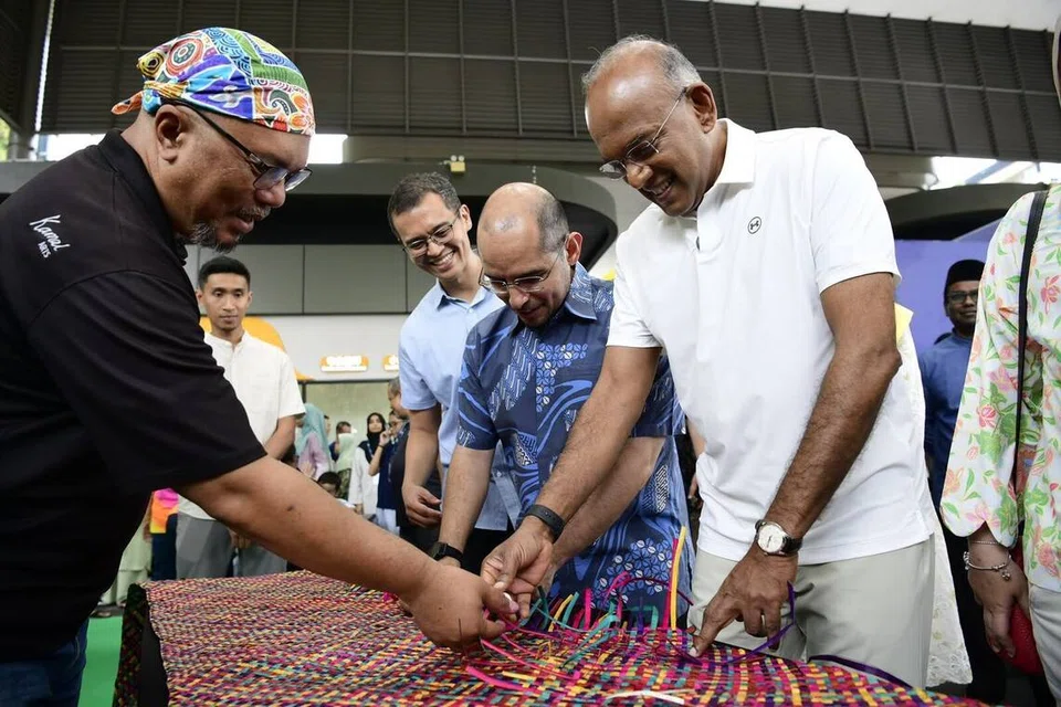Menteri Kanan merangkap Menteri Penyelaras bagi Keselamatan Negara, Encik K. Shanmugam (kanan) dan Setiausaha Parlimen Kanan (Pendidikan merangkap Pembangunan Negara), Dr Syed Harun Alhabsyi (dua dari kanan) mencuba aktiviti menganyam dengan bimbingan pengasas Kamal Arts, Encik Kamal Dollah (kiri), semasa Raikan Ilmu@Heartlands (Nee Soon) di Yishun Town Square pada 5 September. Turut bersama dalam gambar ialah Pengerusi M³+@Nee Soon, Encik Ibrahim Ghouth Wu (tiga dari kanan).