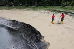 Sekumpulan pekerja membersihkan tumpahan minyak yang dikesan di perairan East Coast Park pada 15 Jun.