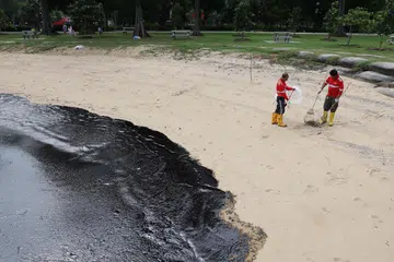 Sekumpulan pekerja membersihkan tumpahan minyak yang dikesan di perairan East Coast Park pada 15 Jun.