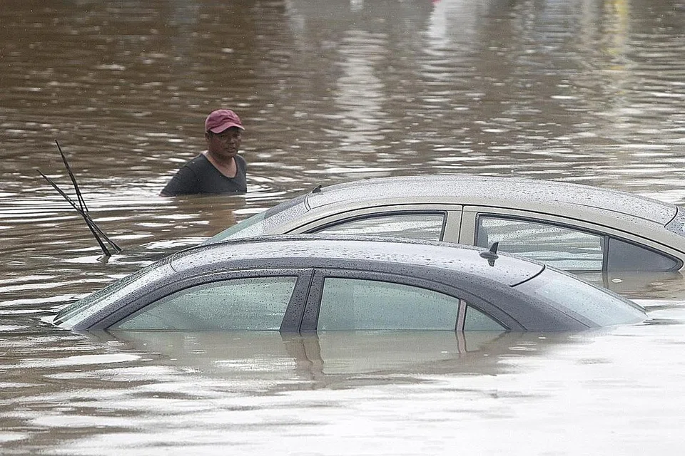 DITENGGELAMI: Seorang lelaki jalan melewati kereta yang ditenggelami air banjir hampir sepenuhnya di sebatang jalan raya di Jakarta pada Tahun Baru. Hujan tanpa henti dari malam 31 Disember hingga esoknya turut menyebabkan banyak kenderaan terkandas dan jalan raya tidak dapat dilalui lalu lintas. - Foto EPA-EFE