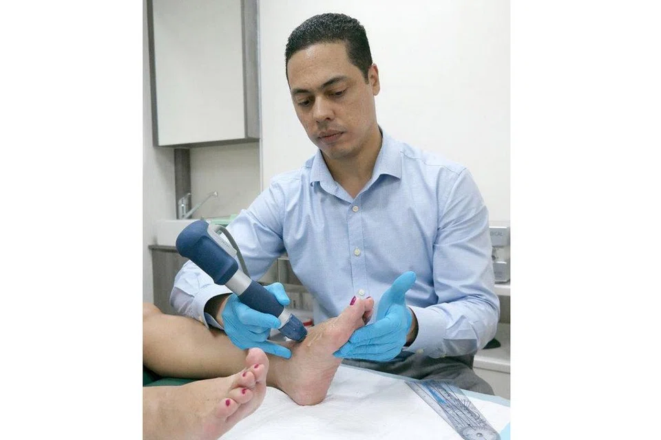 RAWATAN 'SHOCKWAVE': Encik Mark Reyneker menjalankan rawatan terapi 'shockwave' ke atas kaki Cik G. Wong yang mengalami masalah 'bunion'. - Foto-foto ihsan SHAH RIZAL