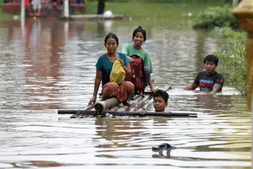 Para penduduk mengharungi air banjir dengan rakit di Taungoo, bahagian Bago, Myanmar, pada 16 September akibat hujan lebat ekoran Taufan Yagi, menyebabkan banjir teruk di beberapa wilayah di negara itu.