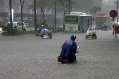 Orang ramai meredah banjir sambil menolak motosikal mereka di sebuah jalan yang ditenggelami air di Hanoi, Vietnam, pada 30 September 2025. Taufan Bualoi telah meragut sekurang-kurangnya 19 nyawa, mencederakan puluhan orang dan menyebabkan beberapa lagi hilang sejak ia melanda kawasan utara-tengah Vietnam, menurut media negara.