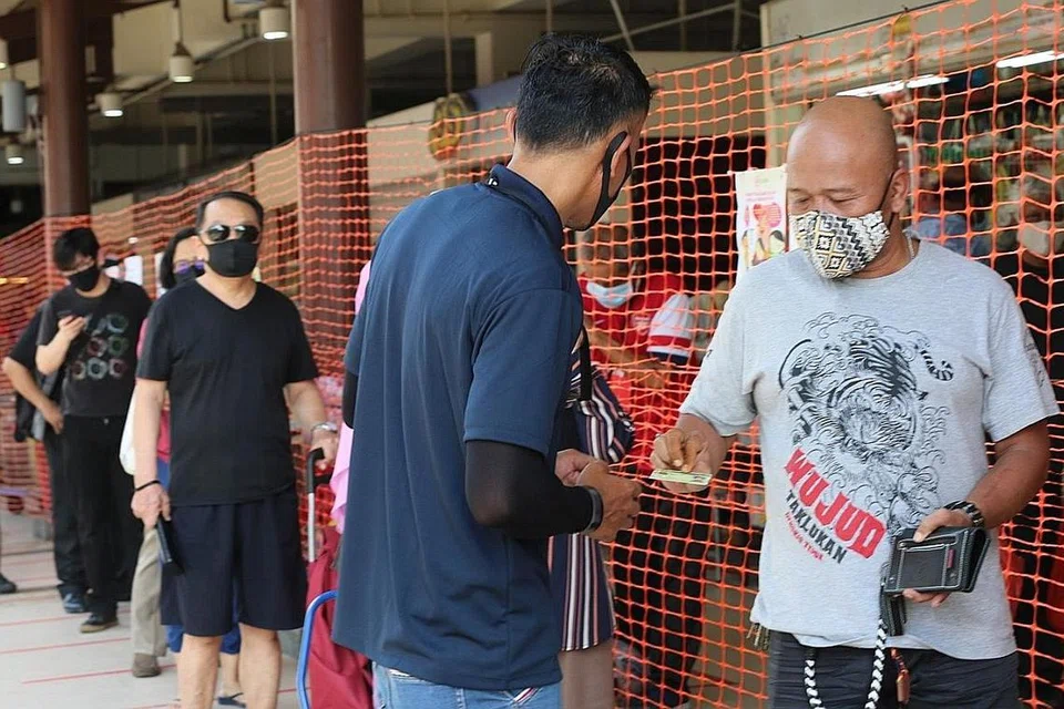 LANGKAH DIPERKETAT: Pengunjung ke Pasar Geylang Serai semalam perlu menunjukkan kad pengenalan sebelum memasuki pasar.- Foto SHINMIN 