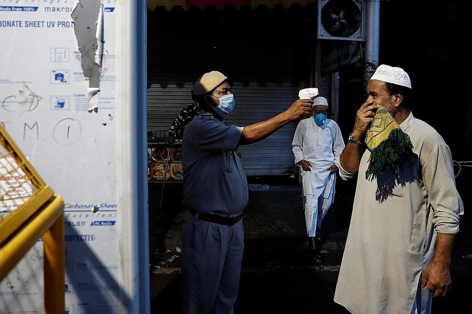 (INDIA) PERIKSA SUHU BADAN: Seorang anggota polis mengambil suhu badan pengunjung yang tiba bagi solat Aidiladha di Masjid Jama di New Delhi, India. - Foto REUTERS 