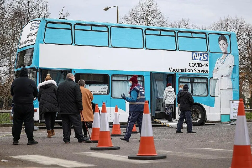 DAPATKAN VAKSIN: Orang ramai beratur di luar bas yang diubah menjadi pusat vaksinasi bergerak bagi koronavirus di Thamesmead, London. - Foto REUTERS