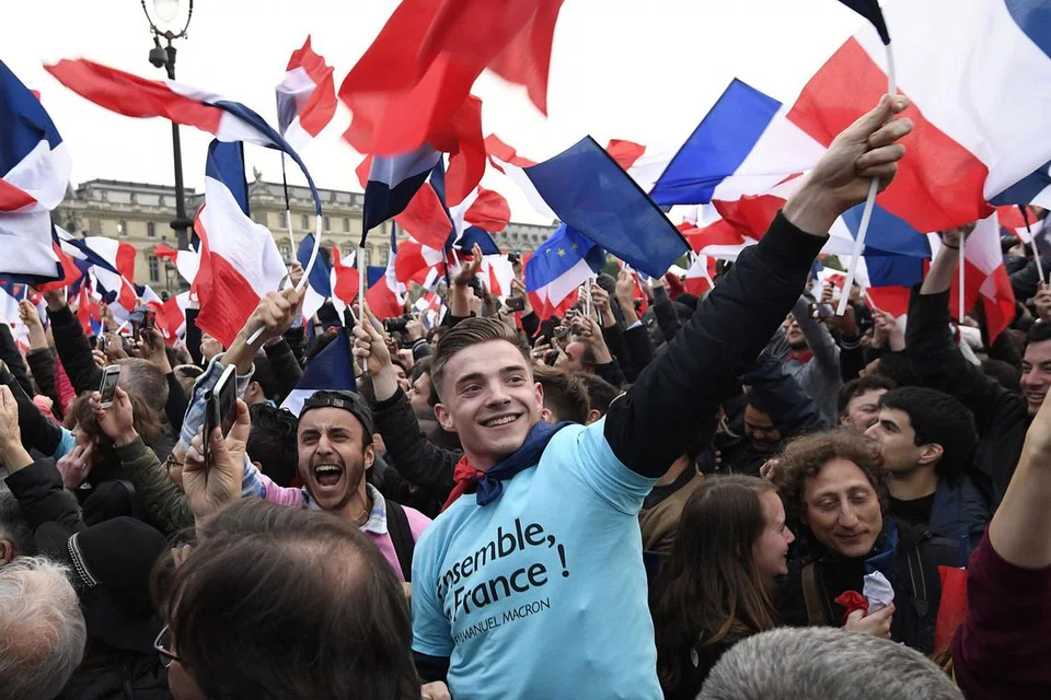 RAIKAN KEMENANGAN: Penyokong Encik Macron berhimpun di depan Muzium Louvre sambil mengibarkan bendera negara. - Foto AFP 
