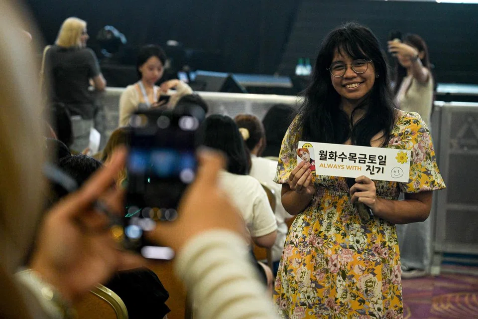 Peminat kelihatan gembira mengambil gambar sambil memegang sepanduk di acara temu peminat, ‘GUESS! Onew FanMeeting 2024’. 