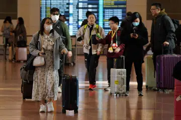 Pelancong membawa bagasi mereka di lobi Lapangan Terbang Haneda di Tokyo.