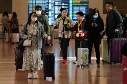Pelancong membawa bagasi mereka di lobi Lapangan Terbang Haneda di Tokyo.
