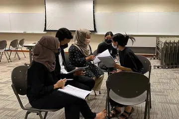 BIMBING PELAKON: Cik Nur Nadia (kanan) sedang membimbing para pelakon dengan penerangan skrip hasil karya beliau dan Cik Nuryn Iman (tiada dalam gambar).