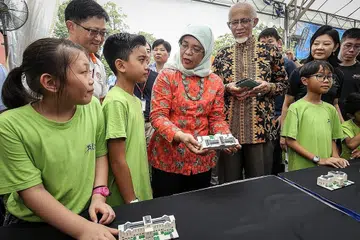SAMBUT TETAMU, INGATI SEJARAH: Presiden Halimah (dua dari kanan) berbual dengan pengunjung cilik ke Rumah Terbuka Istana semalam. Bersamanya ialah suaminya, Encik Mohamad Alhabshee (kanan). Puan Halimah melancarkan model Istana eksklusif, yang diperbuat daripada Lego, sempena memperingati ulang tahun ke-150 Istana. - Foto ZAOBAO
