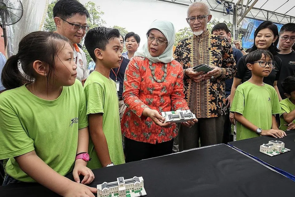SAMBUT TETAMU, INGATI SEJARAH: Presiden Halimah (dua dari kanan) berbual dengan pengunjung cilik ke Rumah Terbuka Istana semalam. Bersamanya ialah suaminya, Encik Mohamad Alhabshee (kanan). Puan Halimah melancarkan model Istana eksklusif, yang diperbuat daripada Lego, sempena memperingati ulang tahun ke-150 Istana. - Foto ZAOBAO