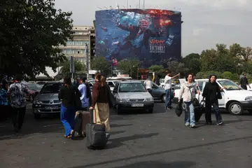 Orang ramai berjalan berhampiran papan iklan memaparkan Presiden Amerika Syarikat, Encik Donald Trump, di sebuah bangunan di Teheran, Iran, pada 22 Ogos 2026. Ketegangan antara Teheran dengan Washington kembali meningkat ketika Iran merancang mengenakan bayaran ke atas kapal dagang yang melalui Selat Hormuz dan memberi amaran kapal yang melanggar peraturan transitnya boleh didenda, ditahan atau dirampas. Amerika pula merancang mengenakan sekatan ekonomi lebih ketat terhadap Iran ketika rundingan mengenai aturan pelayaran di laluan strategik itu masih menemui jalan buntu.