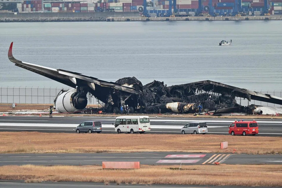 SIASAT PUNCA NAHAS: Para pegawai berada di lokasi serpihan pesawat penumpang Japan Airlines (JAL) yang terbakar selepas bertembung dengan pesawat pengawal pantai di landasan Lapangan Terbang Antarabangsa Tokyo di Haneda.