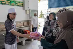 Naib Presiden, Alumni Madrasah Aljunied Singapura (Almas), Ustaz Bahrul-Ulum Buang, mengagihkan bubur kepada penduduk kawasan Geylang Bahru.