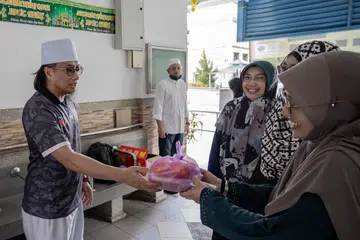 Naib Presiden, Alumni Madrasah Aljunied Singapura (Almas), Ustaz Bahrul-Ulum Buang, mengagihkan bubur kepada penduduk kawasan Geylang Bahru.