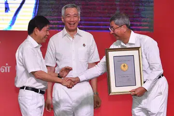 IKTIRAF SUMBANGAN: Mantan pengerusi Parti Tindakan Rakyat Encik Lim Boon Heng (kanan) menerima Pingat Jasa Cemerlang daripada Encik Khaw Boon Wan dengan disaksikan Perdana Menteri Lee Hsien Loong. - Foto BH oleh LIM YAOHUI