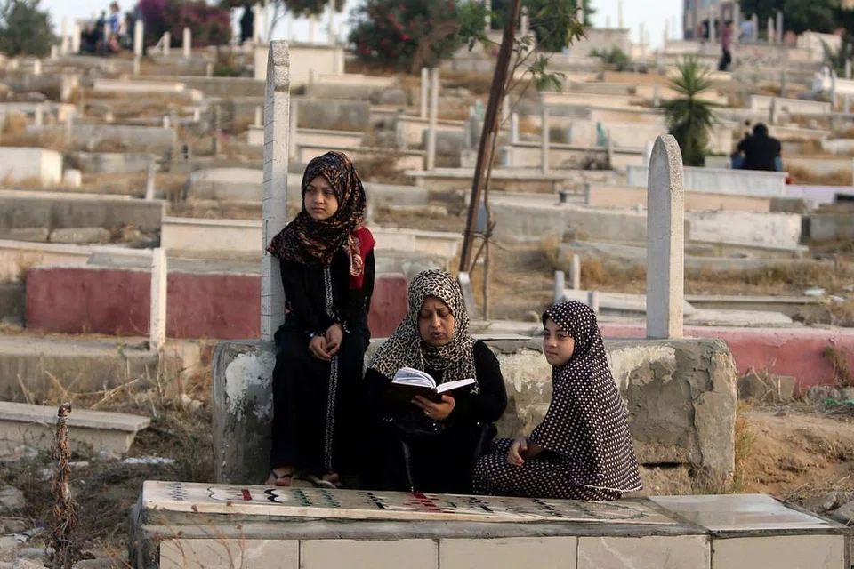 DI PALESTIN: Seorang wanita Palestin membaca Al-Quran di pusara anaknya di Bandar Gaza, kelmarin. - Foto REUTERS