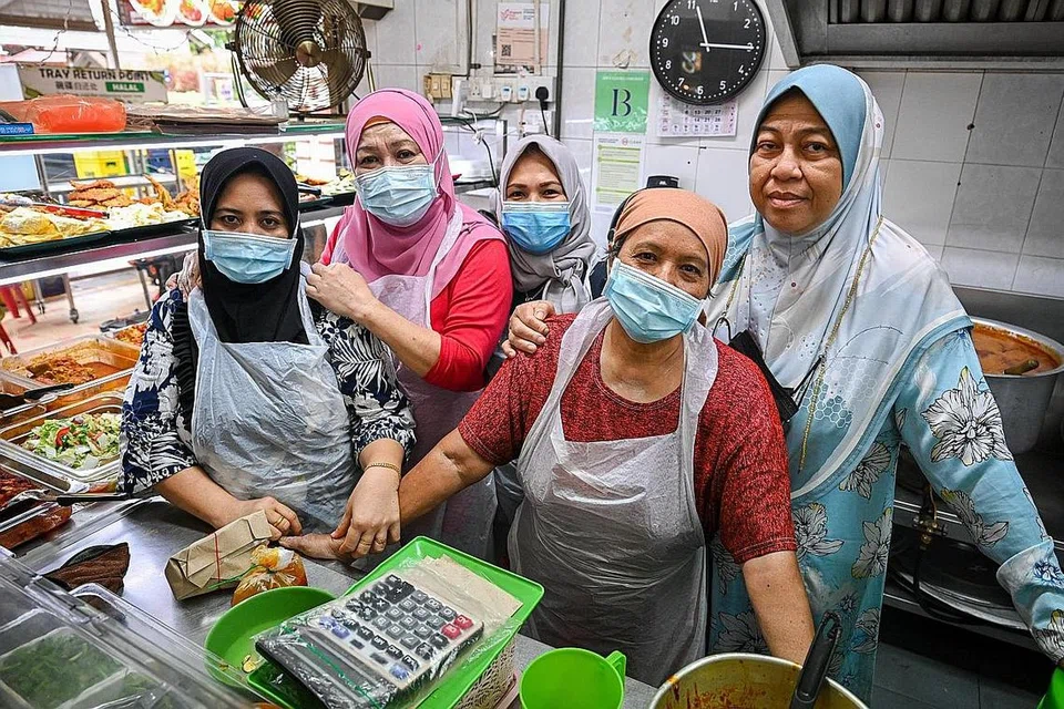 TERUS BERNIAGA: Walaupun perlu menahan sakit di bahagian kakinya akibat ulser kencing manis, Cik Siti Rahimah Edris (gambar atas, paling kanan, bersama empat pekerja di gerainya) tetap pergi ke gerai nasi padangnya di kedai kopi Blok 36, Chai Chee Avenue setiap hari untuk membantu memasak dan melayan pelanggan. Ini kerana beliau amat suka berniaga dan mahu membantu mereka yang kurang berkemampuan dengan menyediakan makanan pada harga yang murah dan berpatutan. - Foto-foto BM oleh SHAFIQ APANDI