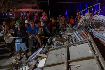 Para penduduk memerhatikan operasi mencari dan menyelamat mangsa yang terperangkap  dalam puing-puing bangunan runtuh akibat gempa bumi di Bogo, Cebu, Filipina, pada 1 Oktober 2025.