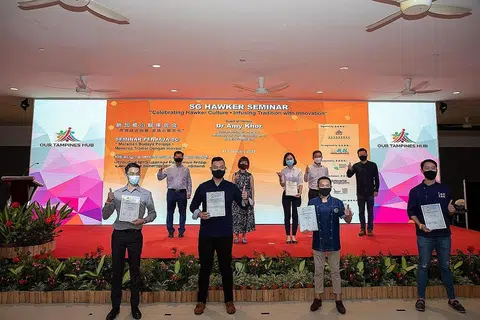 SAMPAIKAN ANUGERAH: Menteri Negara Kanan (Pengangkutan merangkap Kemampanan dan Sekitaran), Dr Amy Khor (di pentas, kedua dari kiri), di acara penyampaian Anugerah Penjaja Singapura kepada 15 penerima semalam semasa Seminar Penjaja SG di Our Tampines Hub. - Foto NEA