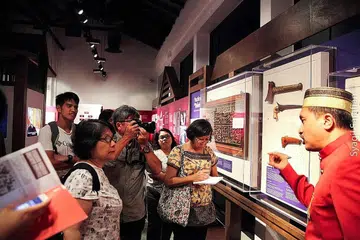 MEMBERI TAKLIMAT: Pengkaji warisan sejarah, Encik Sarafian Salleh (kanan), memberi taklimat kepada pengunjung pameran 'Siri Na Pesse' yang memaparkan lebih 40 artifak yang menceritakan budaya dan sejarah orang Bugis di Singapura. - Foto ENCIK SYAQIL SARAFIAN