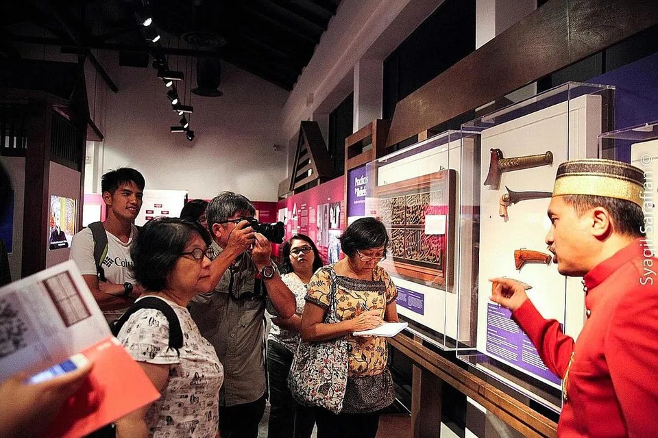 MEMBERI TAKLIMAT: Pengkaji warisan sejarah, Encik Sarafian Salleh (kanan), memberi taklimat kepada pengunjung pameran 'Siri Na Pesse' yang memaparkan lebih 40 artifak yang menceritakan budaya dan sejarah orang Bugis di Singapura. - Foto ENCIK SYAQIL SARAFIAN