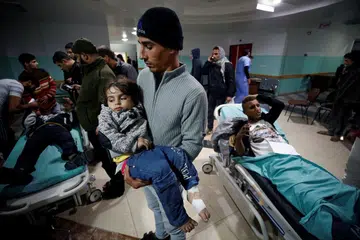 Seorang lelaki Palestin mendukung anak perempuannya semasa menanti mendapat rawatan di sebuah hospital di Jaluran Gaza, ekoran serangan udara dari Israel ke atas sasaran ketenteraan berdekatan pada 8 Disember. 