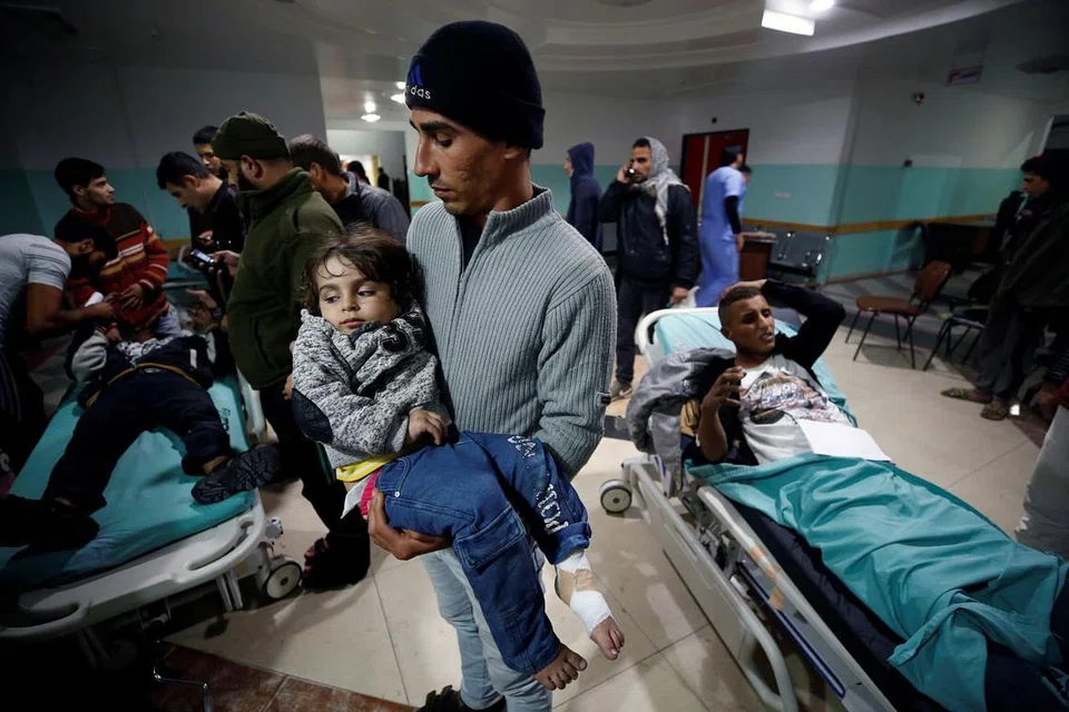 Seorang lelaki Palestin mendukung anak perempuannya semasa menanti mendapat rawatan di sebuah hospital di Jaluran Gaza, ekoran serangan udara dari Israel ke atas sasaran ketenteraan berdekatan pada 8 Disember. 