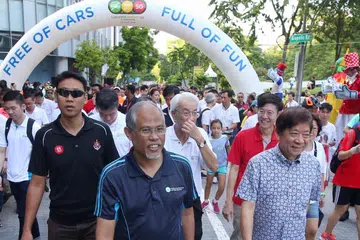 BEBAS BERJALAN: Encik Khaw (kanan) bersama Encik Masagos Zulkifl (tengah, berbaju biru gelap) ditemani orang ramai di acara Bebas Kereta Ahad SG @ one-north. - Foto BH oleh GAVIN FOO