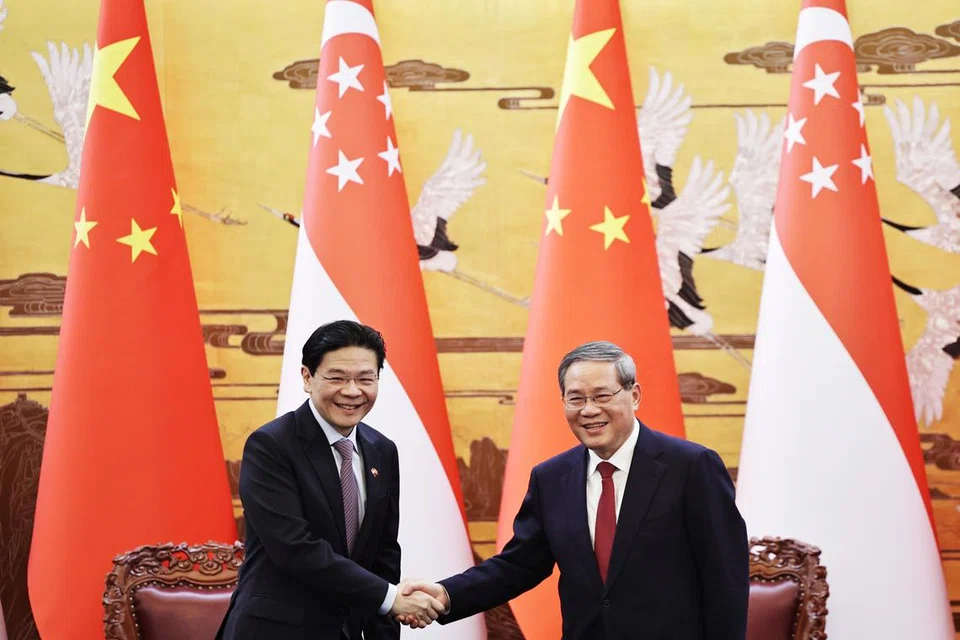 Perdana Menteri, Encik Lawrence Wong (kiri), dan Perdana Menteri China, Encik Li Qiang, berjabat tangan di akhir satu majlis menandatangani perjanjian yang diadakan di Beijing, China pada 23 Jun.