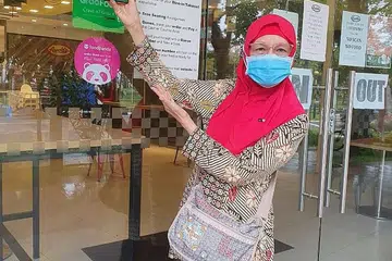 TIDAK KEKOK GUNA TEKNOLOGI: Walaupun telah berusia 67 tahun, Cik Sariah Tomin tidak kekok menggunakan teknologi untuk membuat pembayaran elektronik. - Foto ihsan SARIAH TOMIN