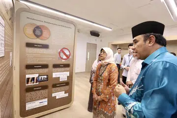 TINGKATKAN KESEDARAN: Ketika melawat Galeri Majulah Kumpulan Pemulihan Keagamaan (RRG) pada Khamis, Presiden Halimah Yacob diberi taklimat oleh pengerusi bersama RRG, Ustaz Dr Mohamed Ali, tentang usaha RRG membolehkan golongan muda mempelajari konsep agama sebenar.