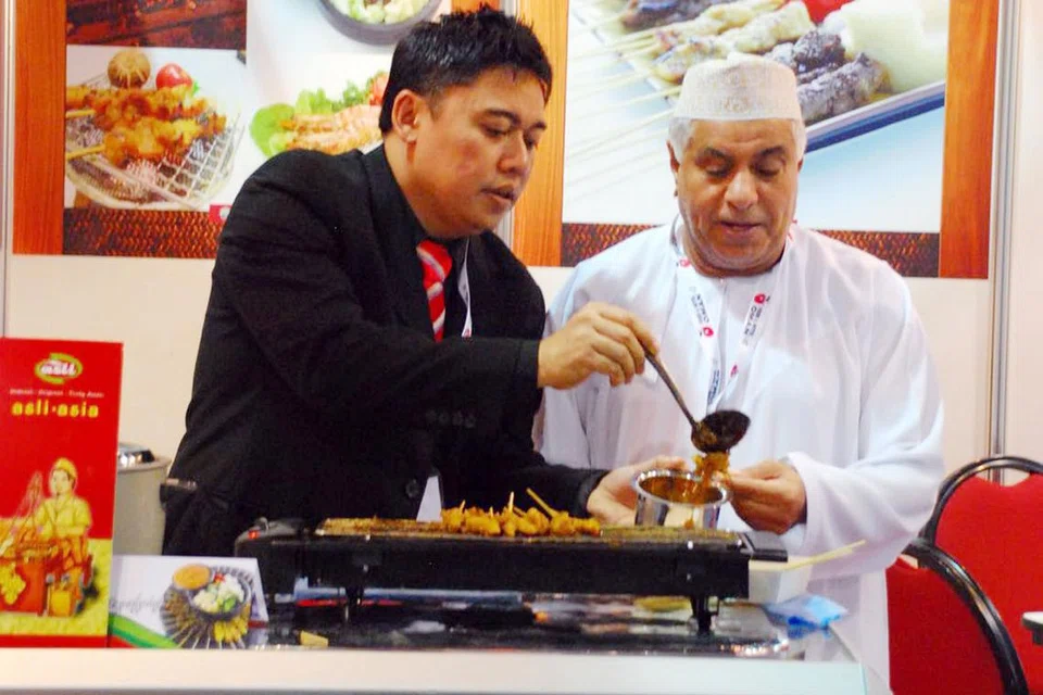 MENYERANTAU: Encik Jefri (kiri) menunjukkan cara menghidangkan sate kepada pengunjung di pameran perdagangan Oman. Encik Jefri dan Cik Samsiah (tiada dalam gambar) rajin menyertai pameran dagangan. - Foto JUMAIN SATAYSFACTION