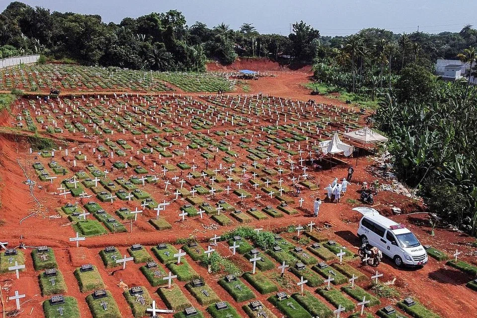 SAYU MEMANDANG: Gambaran dari udara yang menunjukkan pekerja perbandaran lengkap berpakaian kalis kuman mengusung jenazah ke pusara Pondok Ranggon, Jakarta, kelmarin. - Foto REUTERS