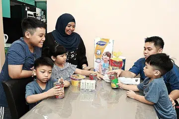 LEBIH BERJIMAT: Cik Nur Diana dan suami Encik Zulfiqar bersama empat anaknya menyemak resit pembelian barangan dapur bagi memastikan ia tidak melebihi bajet bulanan. - Foto BH oleh KHALID BABA