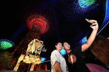 BERMANDI CAHAYA: Encik R. Narindran (kanan) dan Cik Sonia Singh mengambil gambar 'selfie' berlatarkan replika jentera pengangkutan 'All-Terrain Scout Transport' dan pokok 'SaberTrees' di Taman di Pesisiran bagi menyambut Hari Star Wars selama tiga hari di pusat peranginan itu. - Foto-foto THE STRAITS TIMES