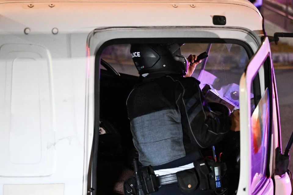 Seorang anggota Pasukan Operasi Khas Polis Trafik (TP) sedang memeriksa label peranti pengehad kelajuan pada sebuah lori semasa operasi penguatkuasaan di Hougang pada 16 Januari.