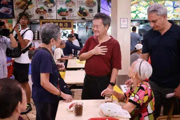 DEKATI PENDUDUK: Mantan Ketua Pegawai Eksekutif (CEO) NTUC Income, Encik Tan Kin Lian (tengah, baju merah), bertemu penduduk di pasar dan pusat makanan di Blok 505, Jurong West Street 52, pada Selasa. 