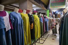 Seorang wanita berjalan melepasi deretan pakaian yang dijual di sebuah pasar di Surabaya pada 8 Julai 2025, ketika pemerintah Indonesia mewajibkan platform e-dagang untuk memungut dan menyerahkan cukai daripada penjual.