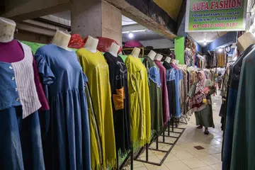 Seorang wanita berjalan melepasi deretan pakaian yang dijual di sebuah pasar di Surabaya pada 8 Julai 2025, ketika pemerintah Indonesia mewajibkan platform e-dagang untuk memungut dan menyerahkan cukai daripada penjual.