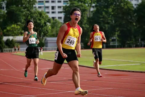 Atlet Institusi Hwa Chong (HCI), Jonathan Hoare (tengah), meraikan kemenangan selepas memenangi acara final 200 meter lelaki Divisyen A dengan catatan masa 22.25 saat di Stadium Choa Chu Kang pada 13 April.