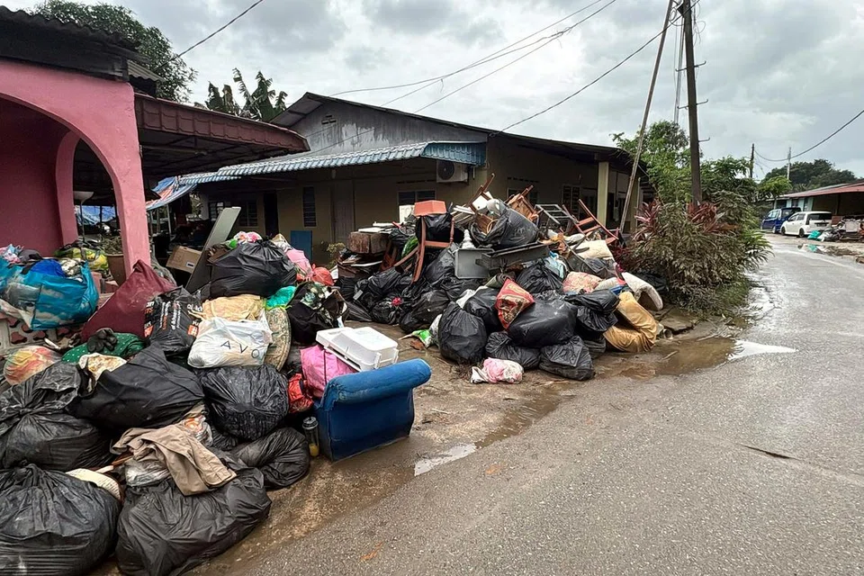 Pelbagai barangan yang musnah akibat bencana bah dilonggokkan mangsa banjir di depan rumah untuk dikutip syarikat konsesi SWM Environment.