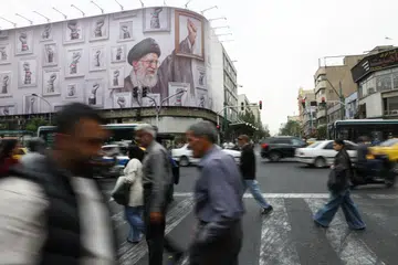Orang ramai berjalan berhampiran papan iklan yang memaparkan imej bekas Pemimpin Tertinggi Iran, Ali Khamenei, di Teheran