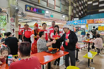 Pengerusi Parti Kemajuan Singapura (PSP), Dr Tan Cheng Bock (kanan), dan Setiausaha Agung PSP, Cik Hazel Poa (dua dari kanan), memberi limau kepada pengunjung di Pusat Makanan dan Pasar West Coast pada pagi 18 Januari.