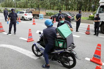 Pegawai polis memeriksa kenderaan di sekatan jalan semasa Perintah Kawalan Pergerakan (PKP), di tengah-tengah wabak penyakit Covid-19 yang meningkat di Malaysia. - Foto REUTERS